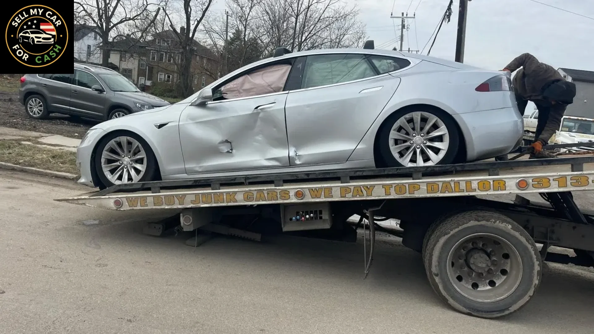 Damaged silver car being loaded onto a tow truck for junk car removal and cash sa